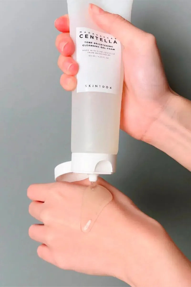 Person dispensing SKIN1004 Tone Brightening Cleansing Gel Foam onto hand for cleansing routine.