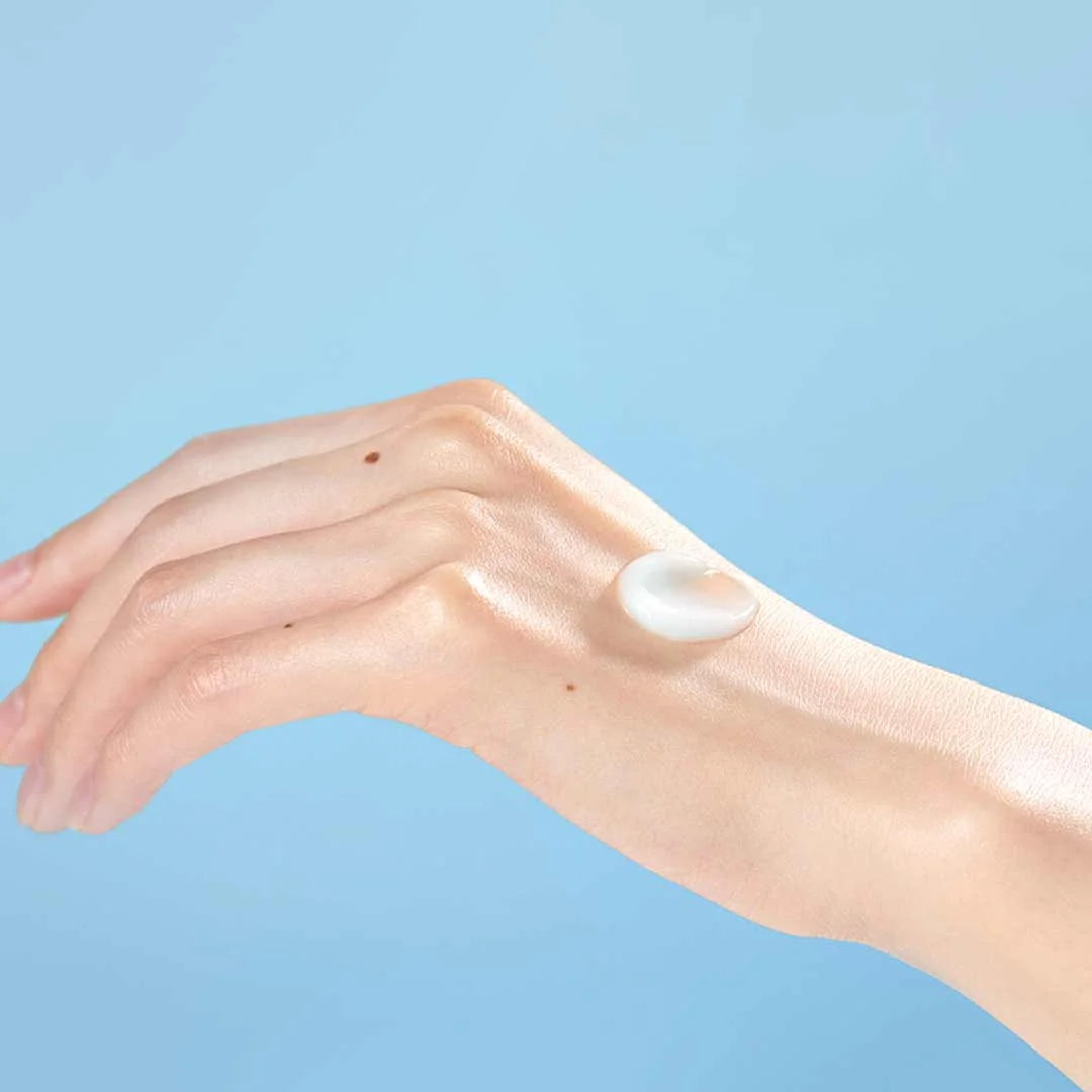 Torriden Dive In Soothing Cream application on hand with soft cream texture against a light blue background.